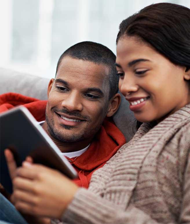 couple on couch looking at a tablet