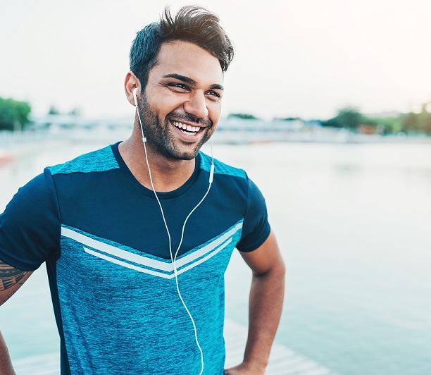 man exercising outdoors while listening to music and smiling