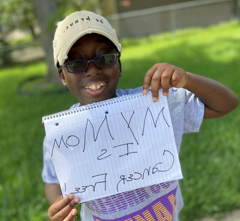 Brittany Clayborne的儿子Micah举着一个牌子，上面写着他的妈妈没有癌症. (图片由Brittany Clayborne提供)